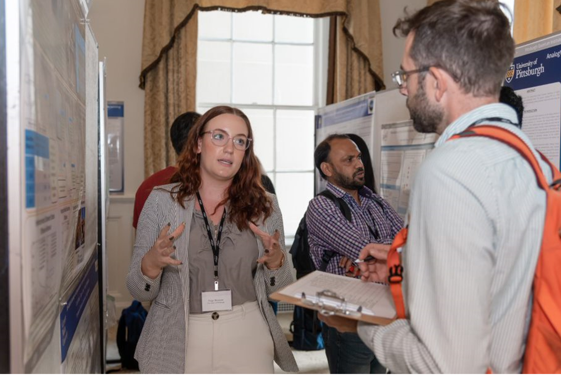 "Paige Moncure presenting her poster Relationship between Gel Mesh and Particle Size in Determining Nanoparticle Diffusion in Hydrogel Nanocomposites to Patrick Irvin during the poster session."