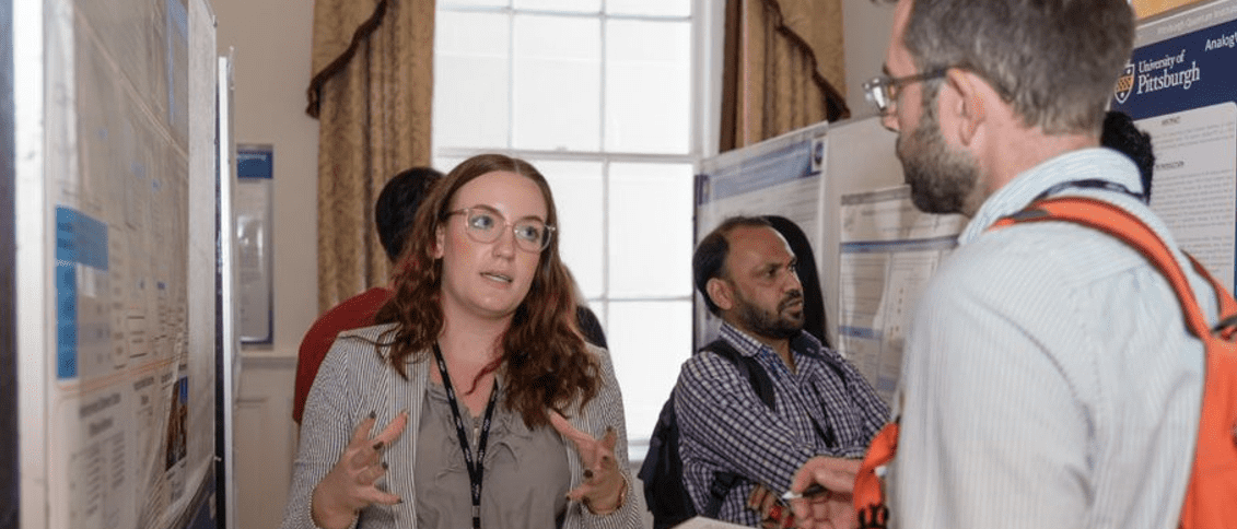 "Paige Moncure presenting her poster Relationship between Gel Mesh and Particle Size in Determining Nanoparticle Diffusion in Hydrogel Nanocomposites to Patrick Irvin."